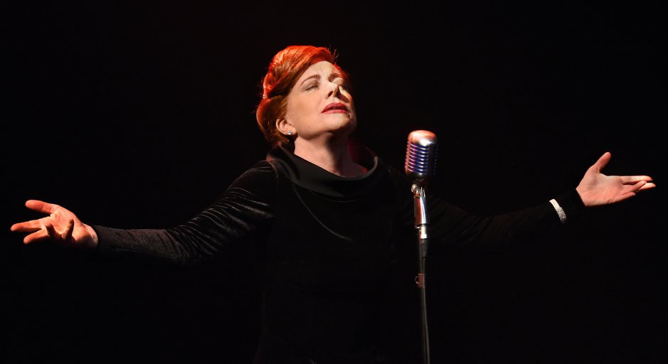 Bernadette Robinson with eyes closed, head tilted upwards and arms spread open