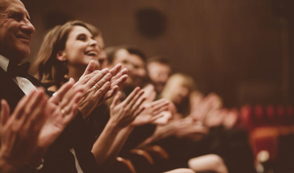 A row of people smiling and clapping