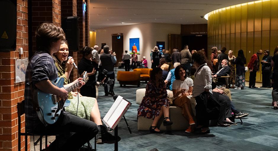 The Round foyer full of people enjoying Fab Fridays with two performers in the foreground.