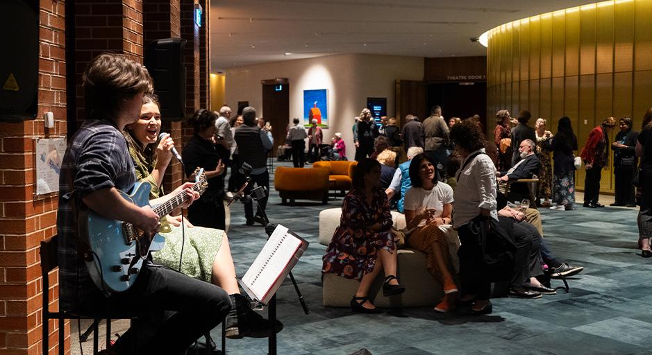 The Round foyer full of people enjoying Fab Fridays with two performers in the foreground. 