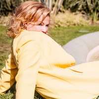 A lady sits on the ground leaning backwards on a very sunny day.