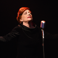 Bernadette Robinson with eyes closed, head tilted upwards and arms spread open