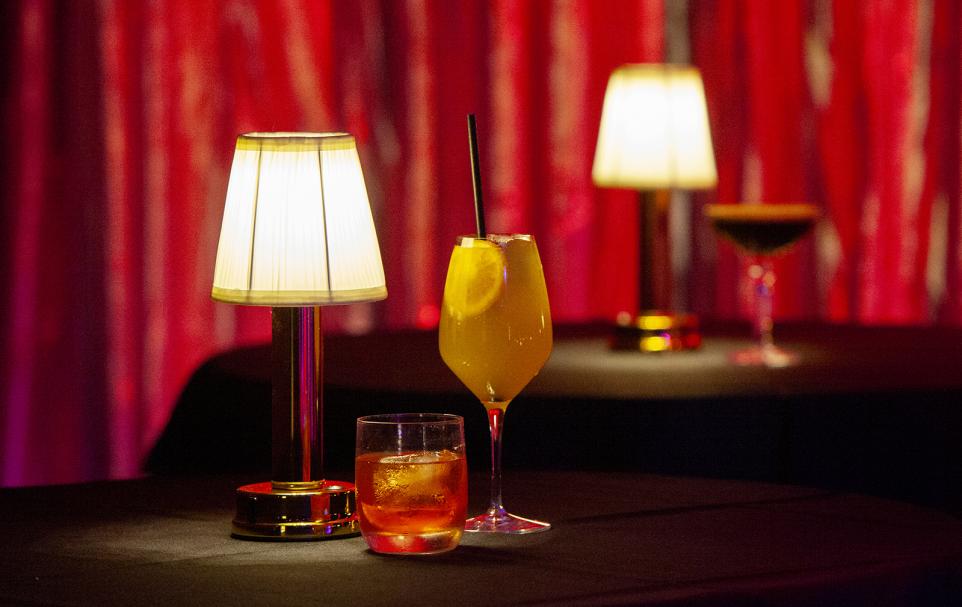 Two different cocktails on a table with table lamps