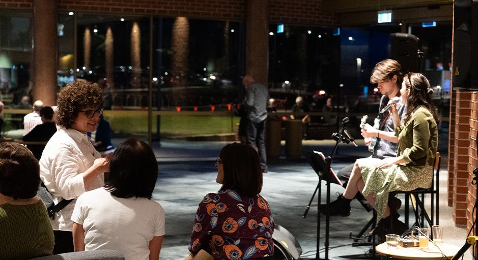 Two performs sing in front of an audience in The Round bar