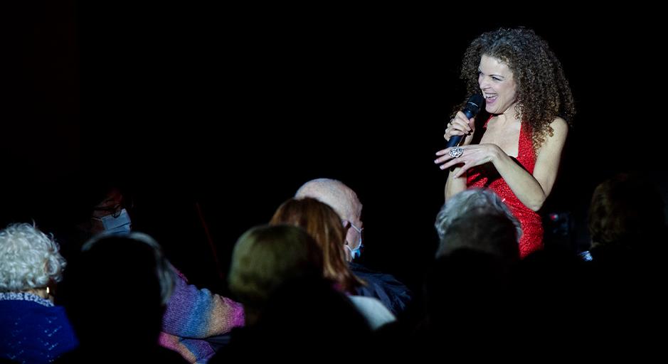A woman in a red dress sings to a crowd