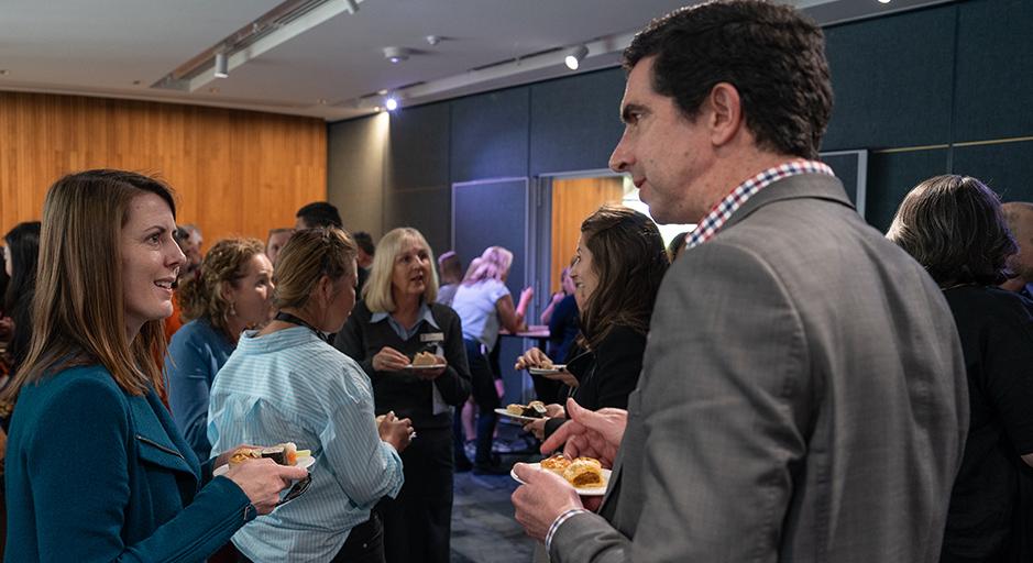 People stand around talking and eating in the function room