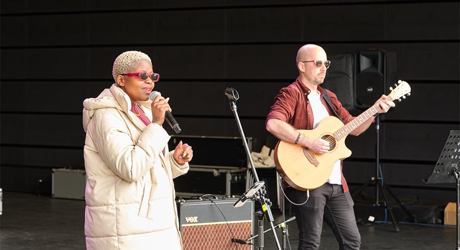 Performers sing and play guitar in the soundshell 