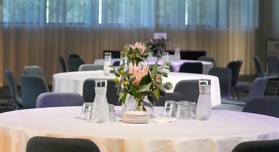 A table is set for a function, with a floral display in the middle